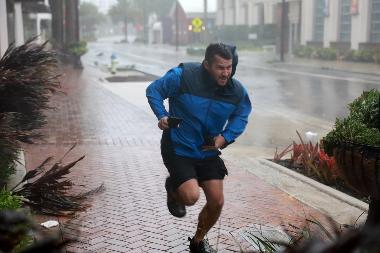 Brent Shaynore corre hacia un refugio en Sarasota, Florida, este 28 de septiembre de 2022. De los 67 condados de Florida, todos ellos declarados en emergencia desde el lunes, 18 emitieron órdenes de evacuación obligatorias ante la llegada de Ian, según el Departamento federal de Manejo de Emergencias (FEMA).
<br>