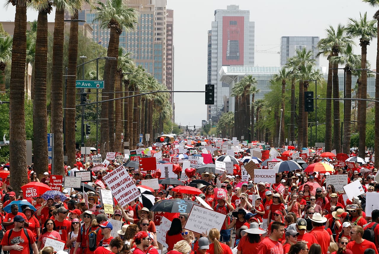 Miles de maestros de Arizona marchan por el centro de Phoenix en su camino hacia el Capitolio estatal este 26 de abril de 2018 en Phoenix, en medio de la huelga para pedir mejores salarios y fondos estatales para escuelas públicas