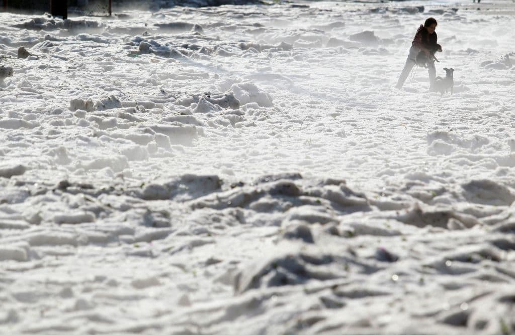 Una mujer y sus perros caminan entre el granizo en las calles de Guadalajara.