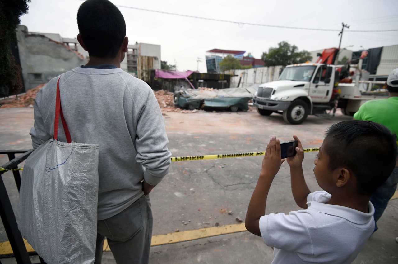 Un menor toma una fotografía al área que fue afectada tras el sismo en la Ciudad de México.