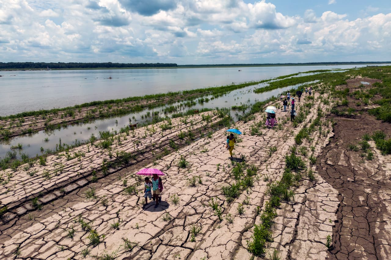 Personas caminan al lado del río Amazonas, en Santa Sofia, Colombia, en octubre de 2024. En medio de 
<a href="https://www.univision.com/shows/noticiero-univision/el-rio-amazonas-se-esta-secando-su-caudal-ha-bajado-casi-un-80-las-imagenes-son-aterradoras-video">una inusual sequía que azotó la Amazonía</a>, la 
<a href="https://public.wmo.int/es" target="_blank">Organización Meteorológica Mundial</a> informaba que el 2024 va camino de convertirse en el más cálido de la historia. La sequía en tres países de la región amazónica, Brasil, Colombia y Perú, están dejando sin comida a 420,000 niños, según UNICEF.
