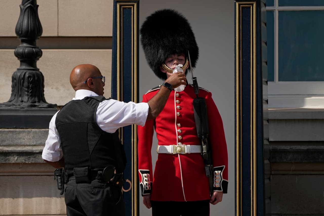 Un oficial de policía da agua a un oficial de la Guardia Real en Londres, Inglaterra, este martes 19 de julio de 2022. La Oficina Meteorológica del Reino Unido registró una lectura provisional de 40.3º C (104.5º F) en Coningsby, en el este de Inglaterra.