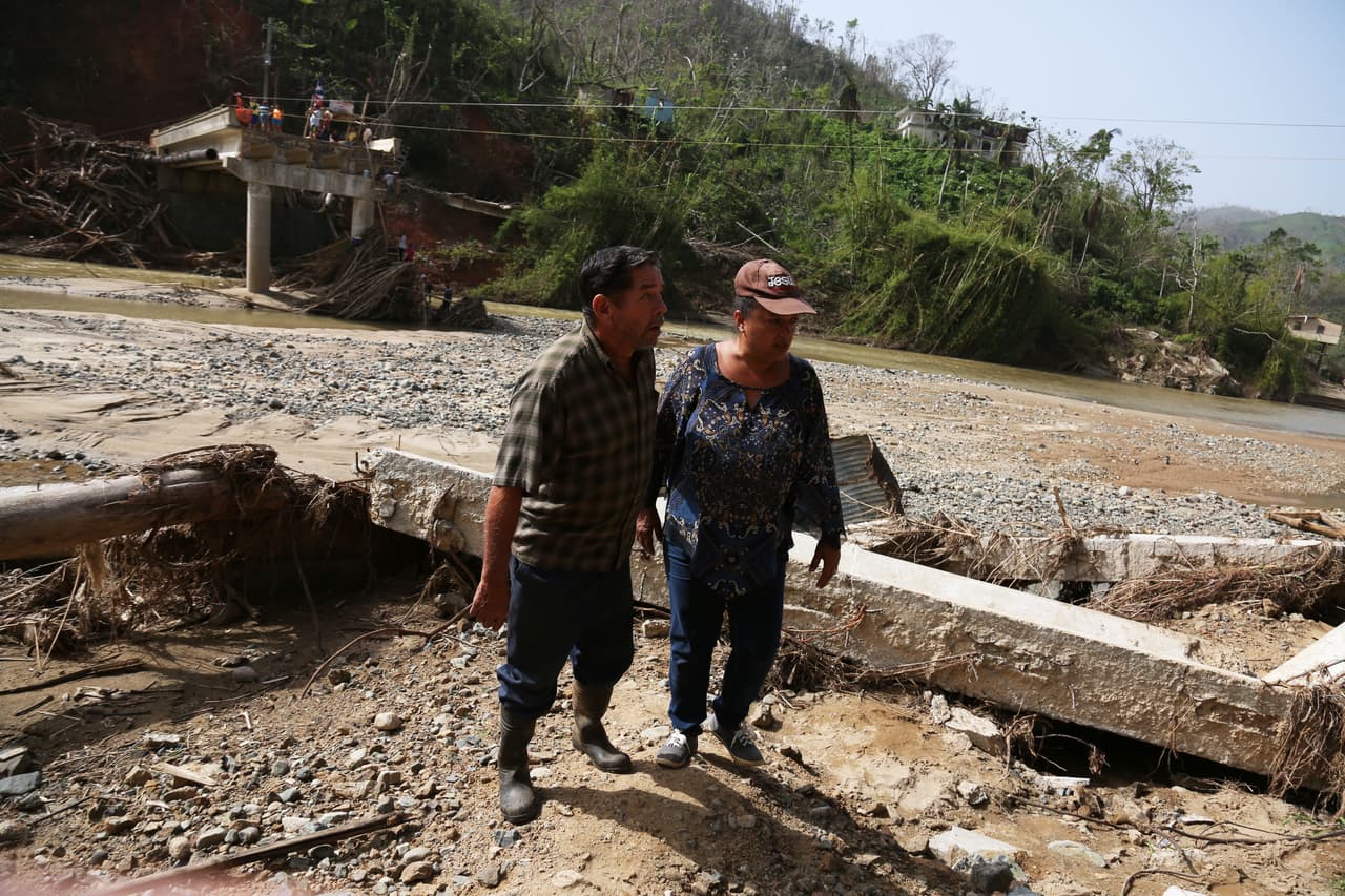 El puente sobre el río Viví en Utuado colapsó con el paso de María. Ángel Reyes y Elba Gómez llevan suministros a través del río a sus familiares del sector Río Abajo.