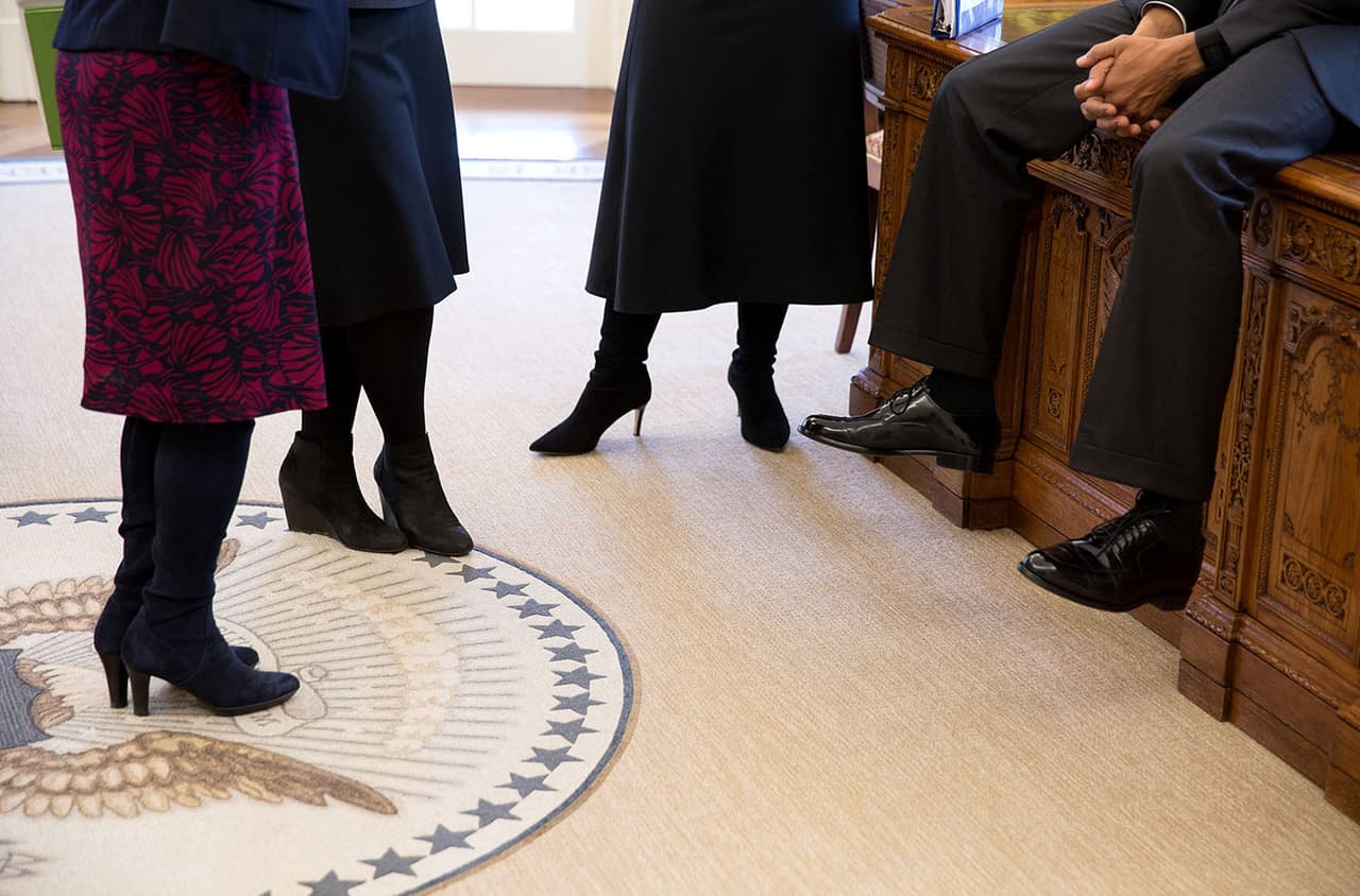 <b>Sus zapatos</b>. Fotografía de los pies de Barack Obama sentado en su escritorio junto a algunas visitantes en la Oficina Oval.