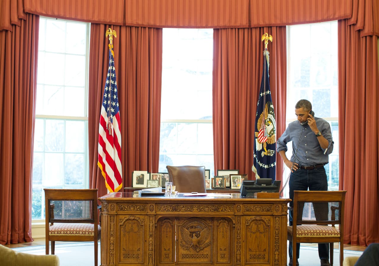 <b>El escritorio de la reina. </b>Barack Obama trabajó sobre el 
<i>Resolute Desk</i>, un escritorio que regaló la reina Victoria al presidente Rutherford B. Hayes en 1880, y fue traído a la Oficina Oval por Jackie Kennedy para su esposo. Desde entonces ha sido usado por varios jefes de Estado: Jimmy Carter, Ronald Reagan, Bill Clinton, George W. Bush y ahora Donald Trump, quien aparentemente continuará trabajando sobre este mueble. Fotografía del presidente demócrata junto al antiguo escritorio, bajo las cortinas rojas de la Oficina Oval, en 2014.
