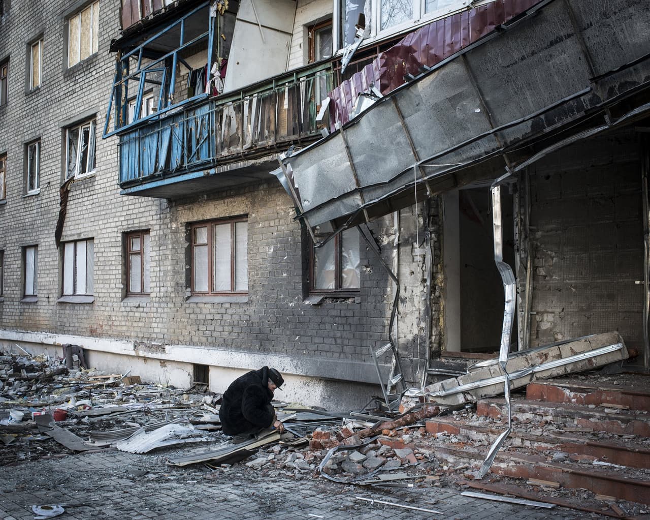 Alexi Stipanovich agachado en las afueras del edificio en el que vivía y que fue bombardeado por proyectiles en la batalla entre los ucranianos y las fuerzas pro rusas en Donbas, Ucrania.