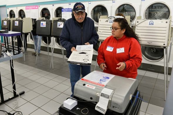 En la imagen la escrutadora electoral Celia Lazalde ayuda al votante Franz Martínez a colocar su sufragio en el lugar indicado.