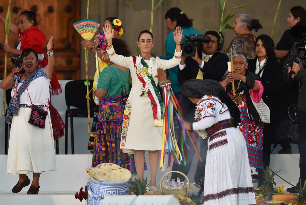 Claudia Sheinbaum (en el centro de la foto), en una ceremonia en la que recibe un bastón ceremonial de manos de indígenas en la Plaza del Zócalo de la Ciudad de México el 1 de octubre de 2024. 
<a href="https://www.univision.com/noticias/america-latina/violencia-en-mexico-masacres-culiacan-sinaloa-sangre-el-inicio-del-mandato-de-claudia-sheinbaum">Sheinbaum marcó la historia como la primera mujer presidenta del país,</a> sucesora de su mentor político Andrés Manuel López Obrador.