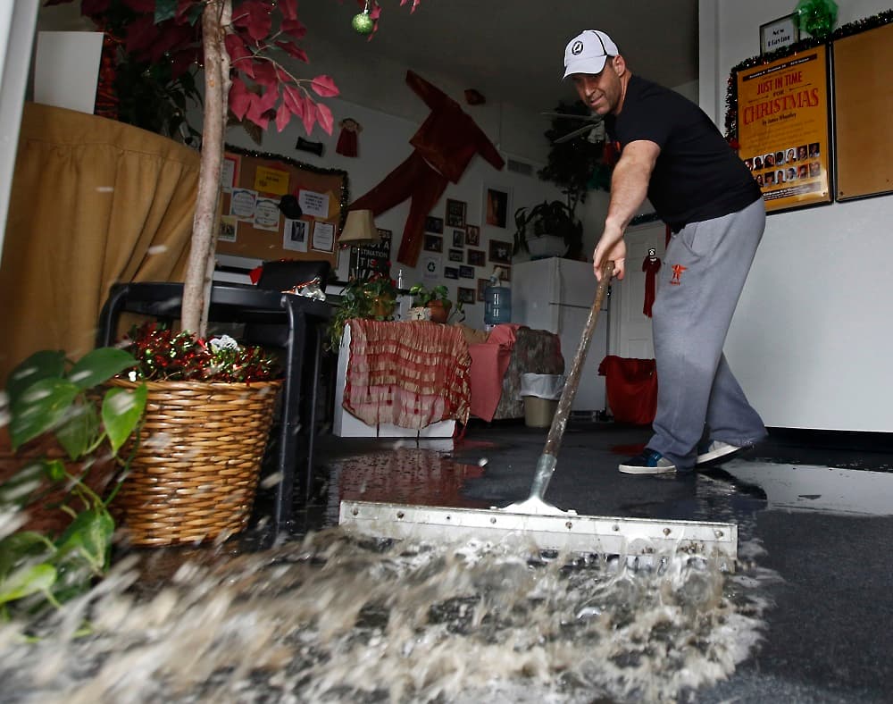 Un residente de Sacramento saca agua de un negocio inundado por las lluvias.