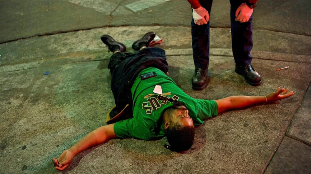 Un paramédico examina a un drogadicto que estaba inconsciente en una acera de Skid Row junto a una jeringa con la que aparentemente se inyectó heroína.