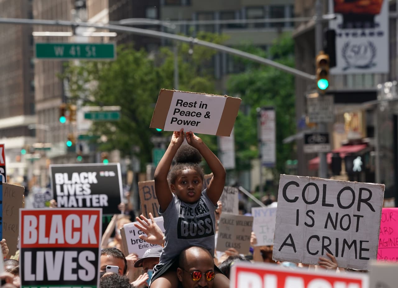 Una niña sujeta una pancarta en Nueva York durante una manifestación en rechazo a la brutalidad policial y el racismo. La protesta tuvo lugar el mismo día que el alcalde de Nueva York Bill de Blasio levantó el toque de queda que estuvo vigente en la ciudad durante casi una semana.