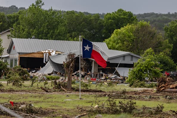 Una bandera de Texas ondea en un campo devastado por las inundaciones en Hunt, Texas.
