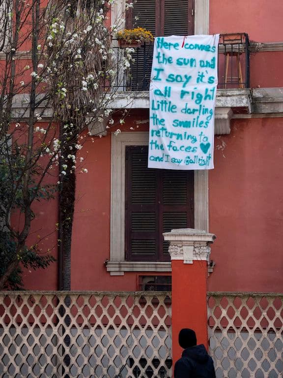Una bandera con la letra de la canción de The Beatles "Here comes the sun". Otro intento para mejorar el ánimo de la gente. En Italia, así como en muchos otros países, las iniciativas online se multiplican, van desde convocatorias a cantar hasta aplausos para el personal médico.
<br>
<br>