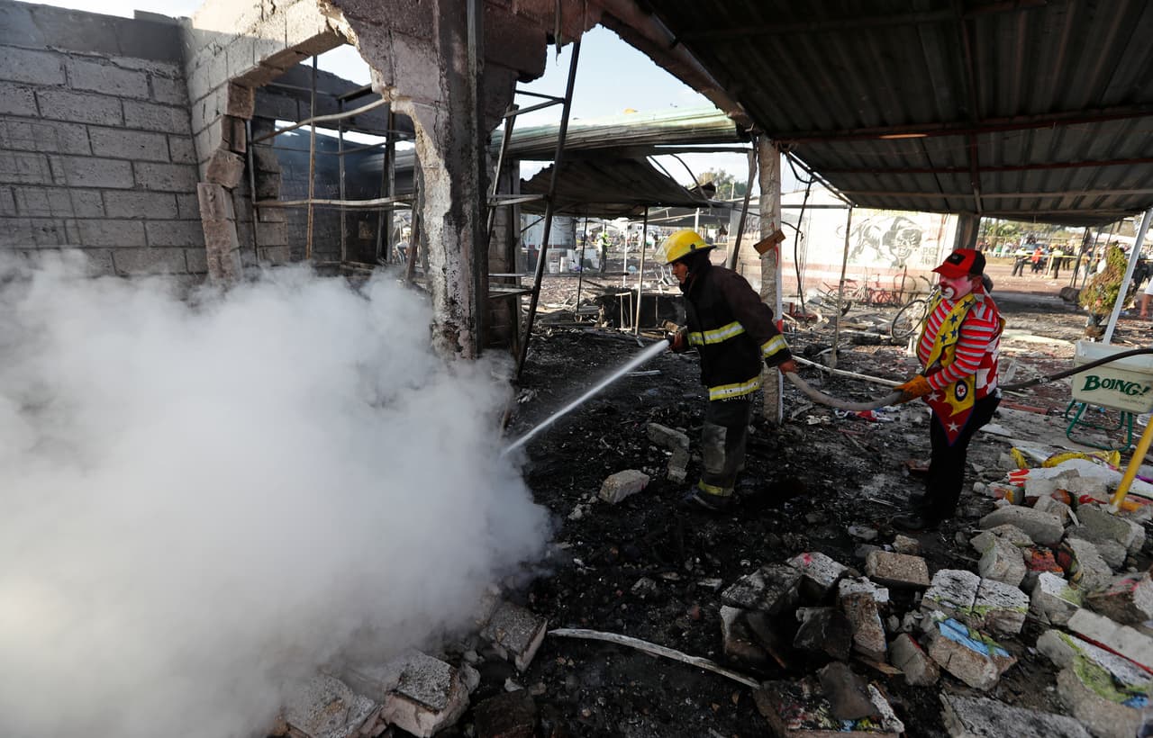 Un residente local vestido de payaso ayuda a un bombero a contener el fuego en el aérea del accidente.