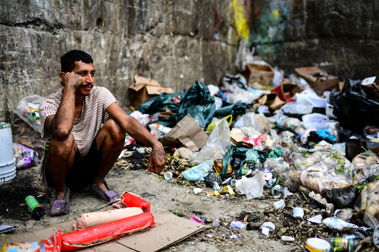 Las pérdidas económicas por los días de apagón nacional ascendían a unos 875 millones de dólares, según los cálculos de la firma consultora local Ecoanalítica, citada por la agencia Reuters. En la fotografía un hombre espera que llegue algo de desechos comestibles a un basurero en Las Minas de Baruta, Caracas.