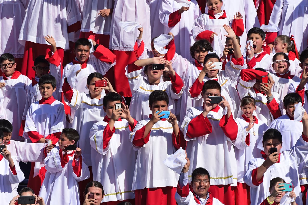 Un grupo de monaguillos toma fotos al Papa desde su celular en el aeropuerto de Ciudad Juárez.