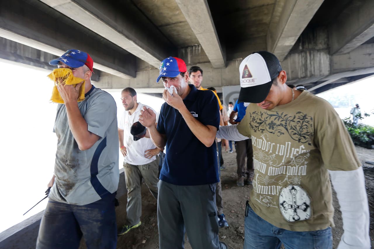 Henrique Capriles, gobernador del estado Miranda y dirigente opositor del partido Primero Justicia, se protege del efecto de los gases lacrimógenos, debajo de la autopista.