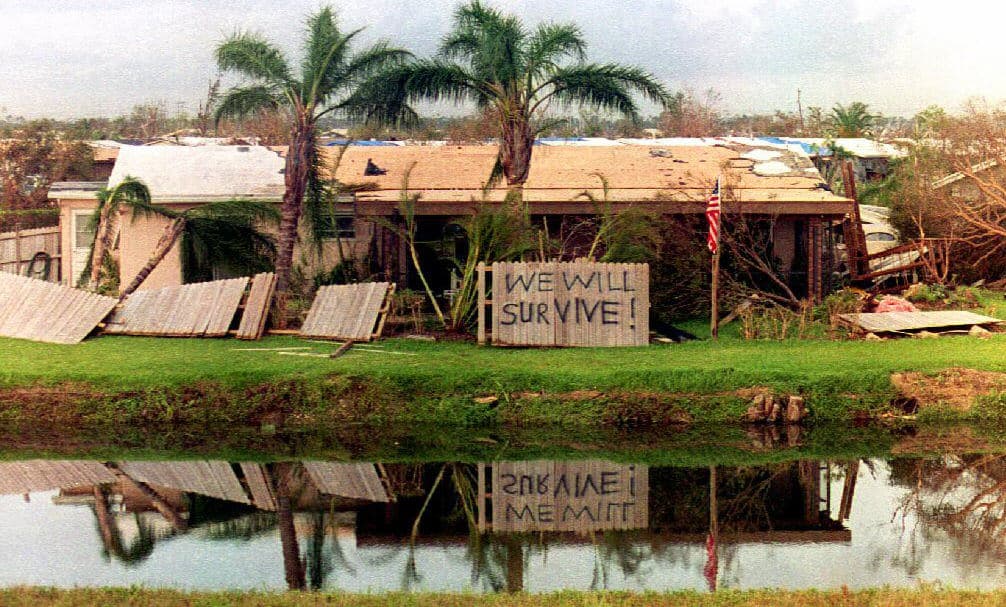 Si la historia se repitiera hoy en Homestead, las cifras treparían de 80,000 a 100,000 millones de dólares, con una cobertura de seguros de 50,000 a 60,000 millones de dólares. En la fotografía, una casa hecha con madera y cartón que sostiene un letrero que dice: "Nosotros vamos a sobrevivir".