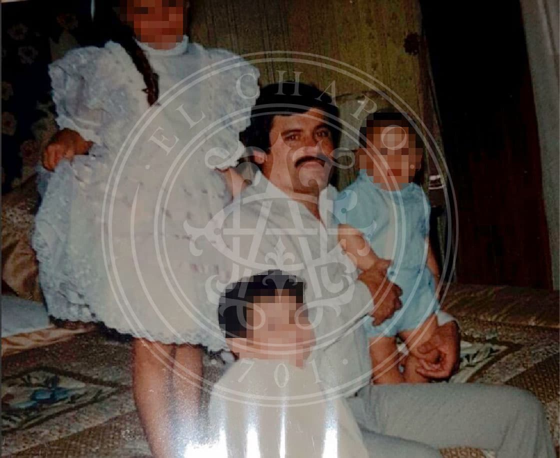 En la cuarta foto, el exjefe del cartel de Sinaloa aparece sentado en una cama con tres niños. Alejandrina Guzmán posa de pie, levantando los olanes de su vestido blanco. Sus hermanos menores también aparecen en ese recuerdo. El narcotraficante lleva un pantalón gris y una camisa blanca de manga larga.