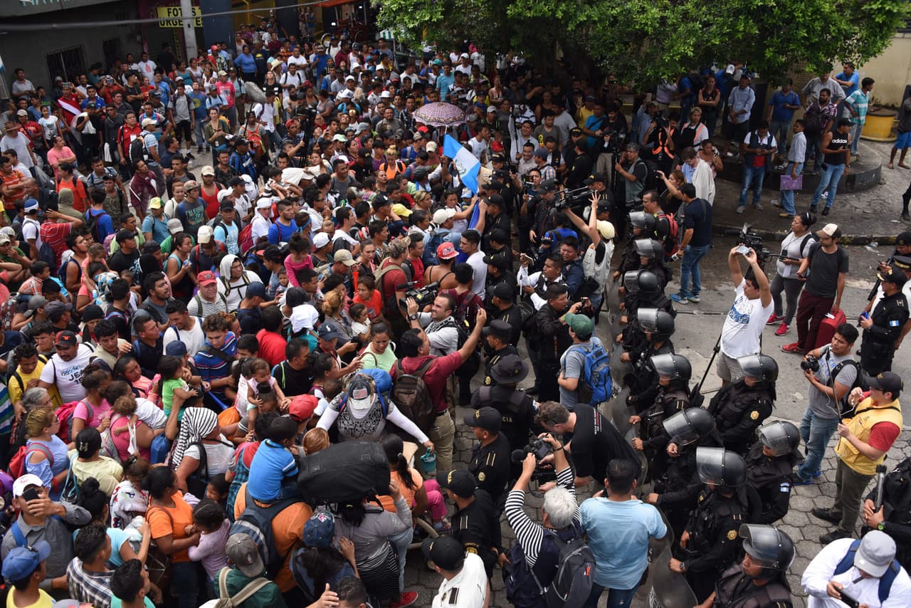 Una fila de policías guatemaltecos intentó detener el paso de los migrantes de la caravana justo antes de una reja amarilla que cerraba el camino hacia el lado mexicano.