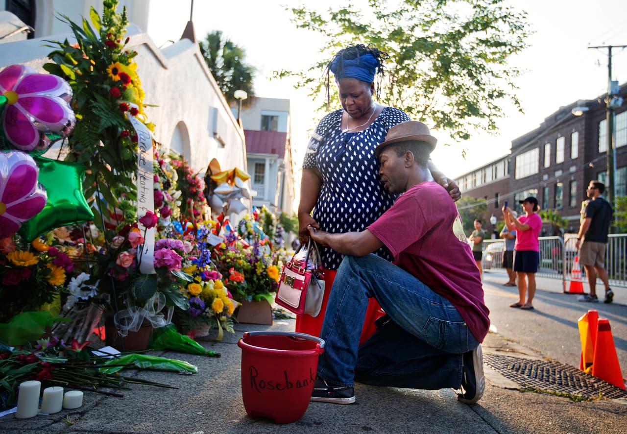 <b>2015. Iglesia en Charleston, Carolina del Sur.</b> Dylann Roof, un supremacista blanco de 19 años,
<b> </b>entró a una lectura de la Biblia en una iglesia de una comunidad afroamericana en la que participaban varios feligreses. Luego de una hora en la reunión sacó su arma y asesinó a nueve personas. 
<a href="https://www.univision.com/noticias/tiroteos/dylann-roof-autor-de-la-masacre-en-la-iglesia-afroamericana-de-charleston-es-sentenciado-a-muerte">Fue arrestado al día siguiente del ataque y condenado a muerte por asesinatos y crímenes de odio.</a> En la fotografía, los miembros de la comunidad donde ocurrió el incidente, Allen Sanders y su esposa Georgette, rezan frente a la iglesia después de la matanza. 17 de junio de 2015.