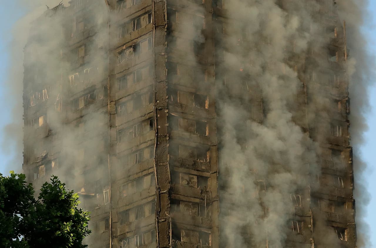 Las cortinas de humo que rodean el edificio donde se desató el incendio, en Londres, la madrugada de este miércoles.