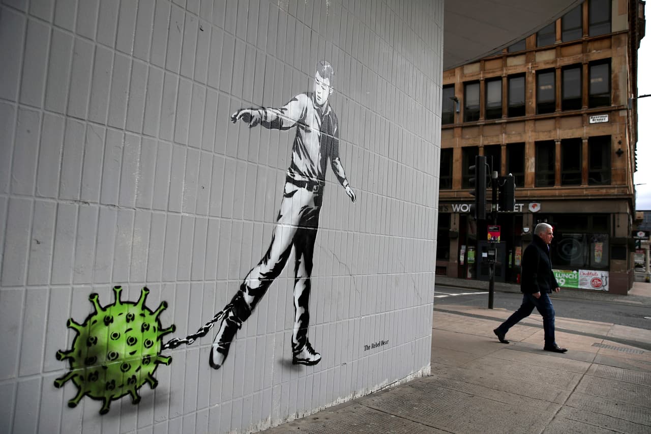 El artista Rebel Bear plasmó su obra, que refleja a un hombre arrastrando un grillete en forma de coronavirus, simbolizando el peso que nos ha tocado cargar y cómo estamos sometidos por esta enfermedad, en una pared de la calle Bath Street en Glasgow, Escocia.