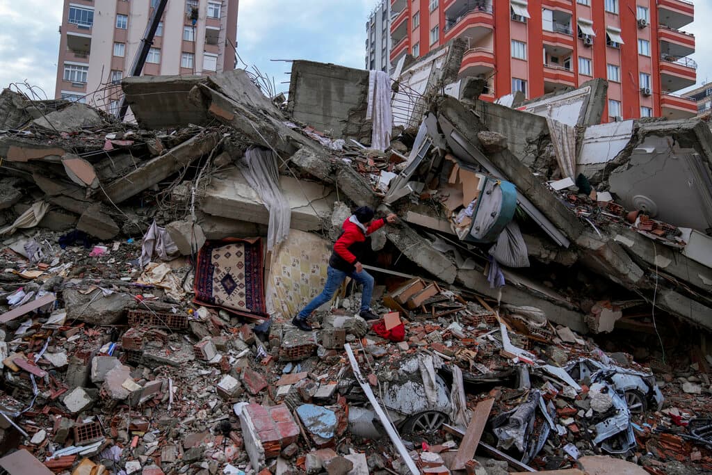 Un hombre camina entre los escombros mientras busca personas en un edificio destruido en Adana, Turquía, el lunes 6 de febrero de 2023.