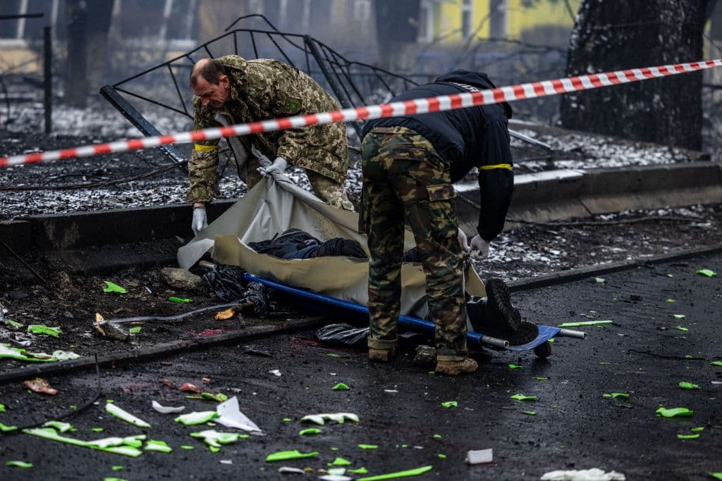 Agentes de seguridad remueven un cuerpo de una calle de Kiev, tras un brutal ataque contra una torre de televisión.