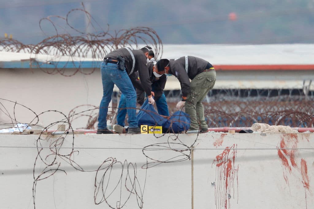 En esta imagen se puede ver a miembros de la policía ecuatoriana sacando el cuerpo de un reo en el techo del penal.