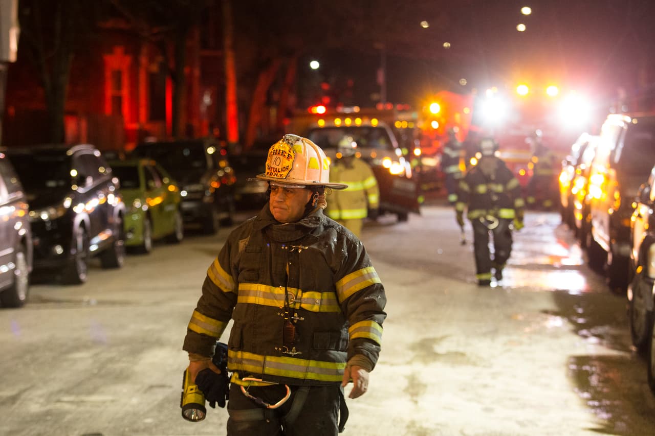 Bomberos caminan por la calle tras apagar el letal incendio en la avenida Prospect en El Bronx.