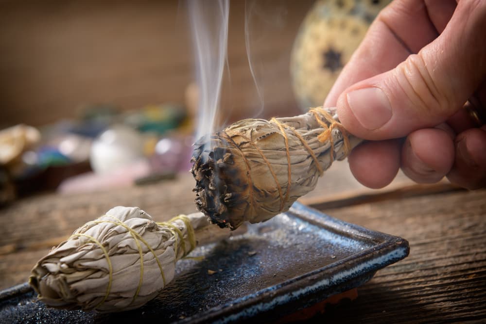 Primero limpia el lugar donde harás tu ritual. Quema una rama de salvia, que es ideal porque está asociada con la luna. Enciende el palo de salvia hasta que tenga una chispa naranja y con su humo pásala alrededor de tu cuerpo y el espacio donde realizarás tu ritual.