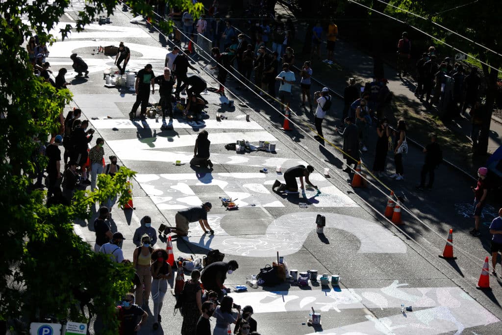 Un grupo de personas plasma en el asfalto de la calle East Pine de Seattle las palabras "Black Lives Matter", el nombre del movimiento que lucha contra la brutalidad policial contra los negros, imitando la iniciativa de la capital, Washington DC, donde 
<b><a href="https://www.univision.com/noticias/sucesos/el-nuevo-nombre-de-esta-calle-frente-a-la-casa-blanca-honra-la-lucha-antirracista-black-lives-matter-fotos-fotos">un gigante cartel de 'Black Lives Matter' en amarillo</a></b> se puede ver en una de las avenidas que conduce a la Casa Blanca.
