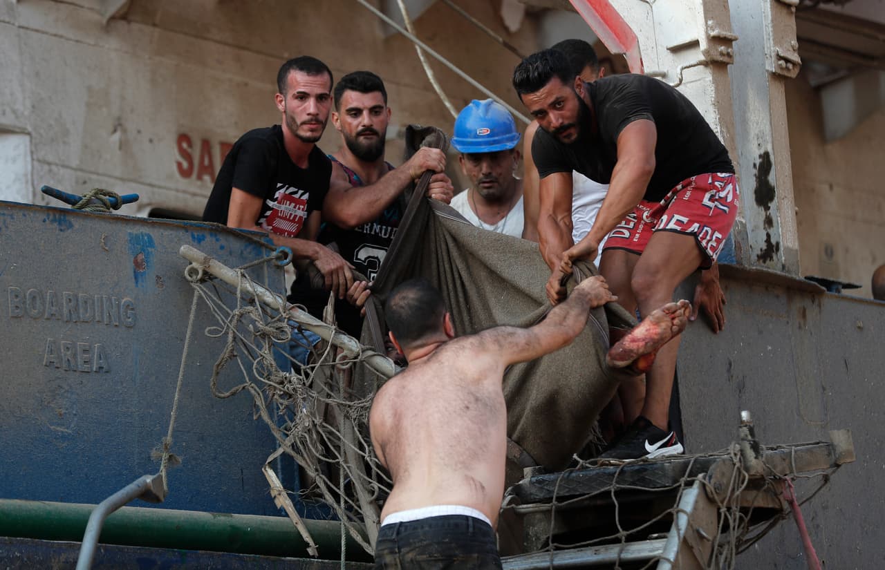 Un grupo de civiles ayudan a los marineros que resultaron heridos en un barco adyacente a la explosión.