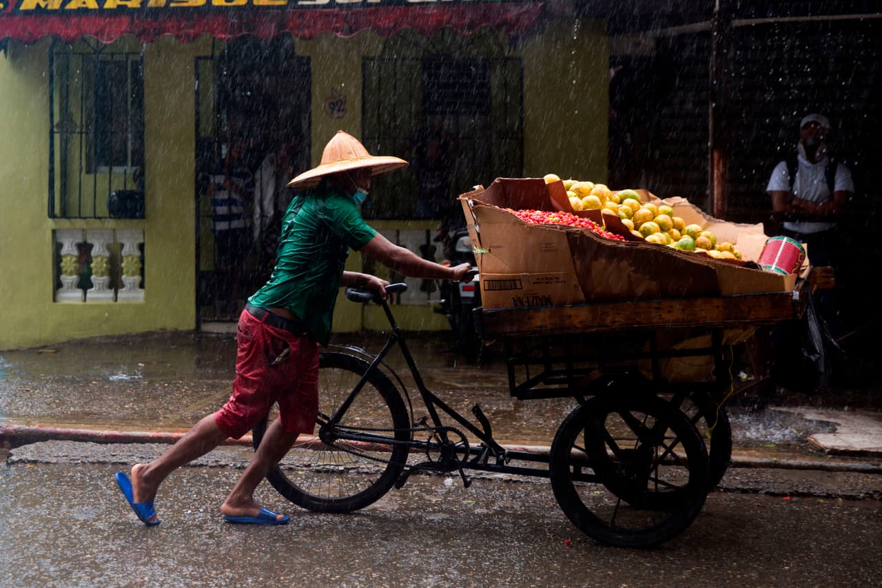 También se reportaron apagones en las vecinas Islas Vírgenes de Estados Unidos. En la fotografía un vendedor de mango bajo la lluvia de Isaías, cuando todavía era considerado tormenta a su paso por Santo Domingo.
<br>