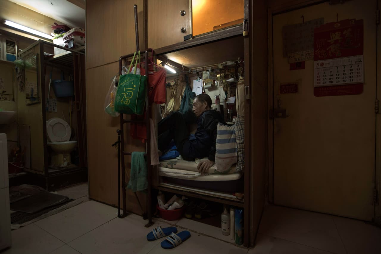 La ‘casa ataúd’ de Wong Tat-ming, de 63 años, está justo al lado de un grupo de inodoros sucios. Paga el equivalente en a 310 dólares al mes por un espacio de tres por seis pies. Está repleto con todas sus escasas posesiones: un saco de dormir, una televisión y un ventilador eléctrico.