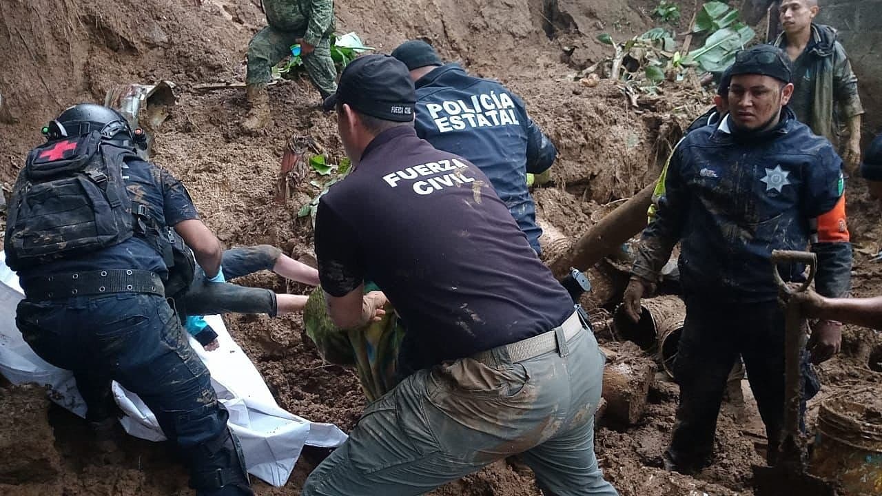 Fotografía cedida por la Fuerza Civil de Veracruz, donde se observa a policías estatales e integrantes de la fuerza civil rescatando cuerpos luego de un deslave este sábado, en el municipio de Xalapa, en el estado de Veracruz.
