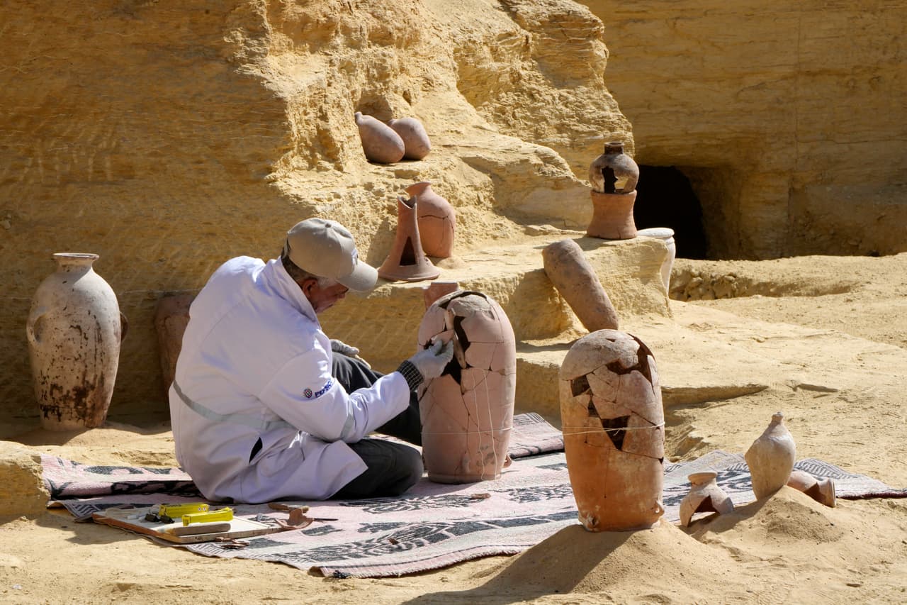 Un arqueólogo egipcio trabaja sobre objetos de cerámica que fueron hallados durante las excavaciones. Cerca de la ciudad de Luxor, las autoridades dijeron que encontraron decenas de sitios de entierro de la era del Nuevo Reino, que datan de 1800 a.C. al 1600 a.C. También hallaron ruinas de una antigua ciudad romana, informaron.
