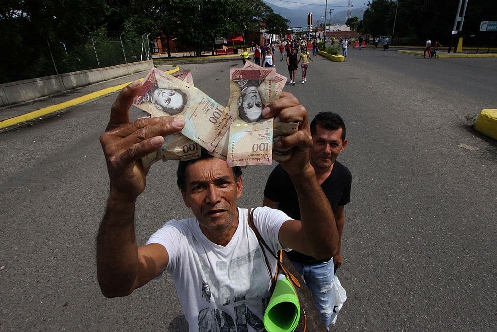 A man shows bills of 100 bolivars while crossing the Venezuelan border of Ureña with Cúcuta, Colombia. Photos: GEORGE CASTELLANOS / AFP / Getty Images.