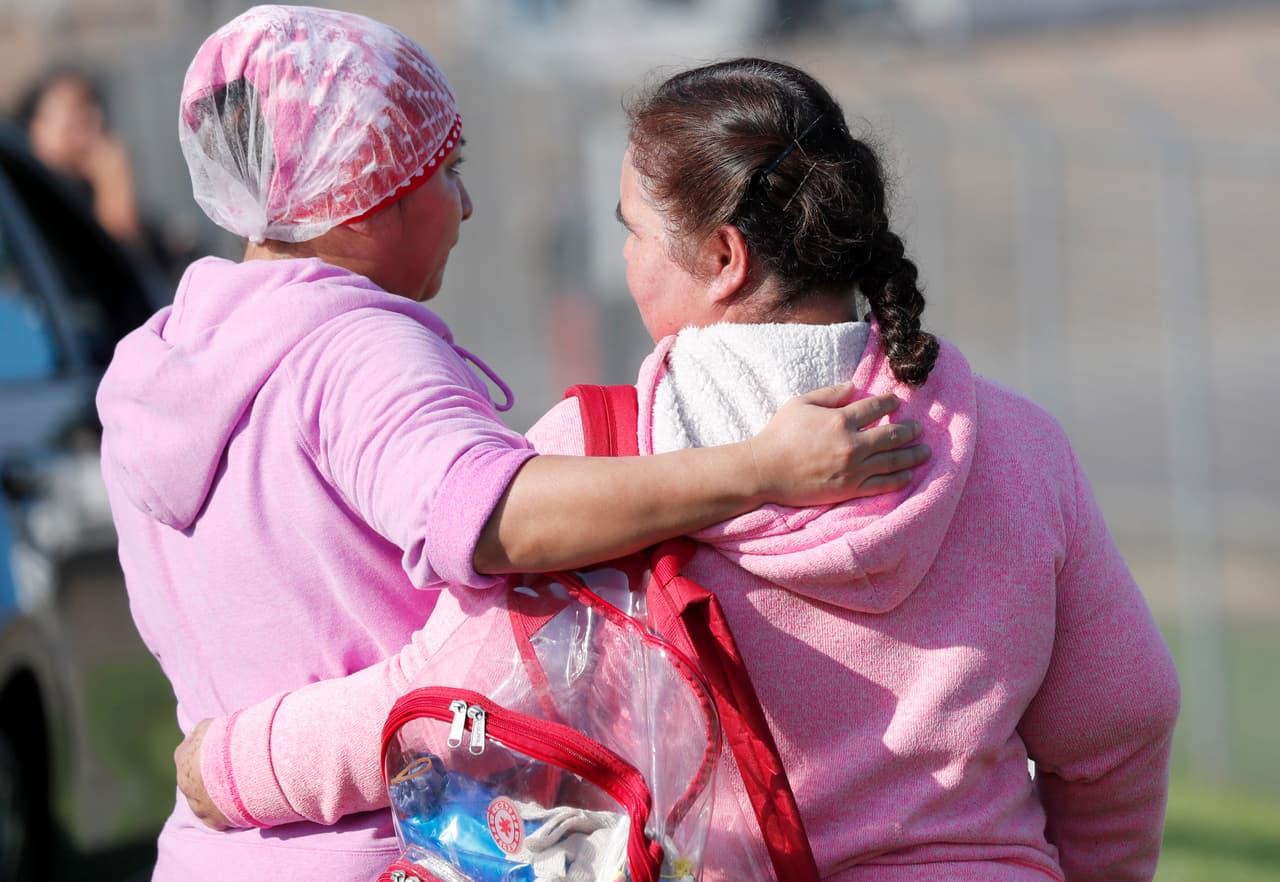 Amigos y familiares de las personas arrestadas se consuelan los unos a los otros tras los arrestos en la planta Koch Foods Inc.
