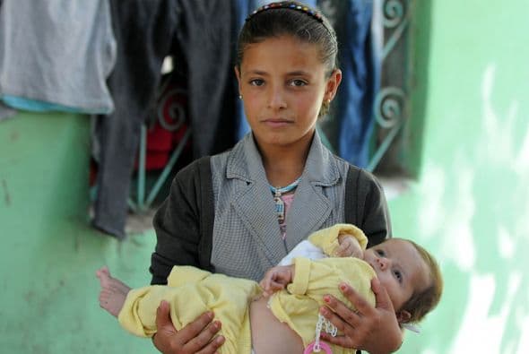 Una niña kurda sostiene a su hermana en una escuela que sirve como refugio temporal en Suruc, provincia de Turquía.