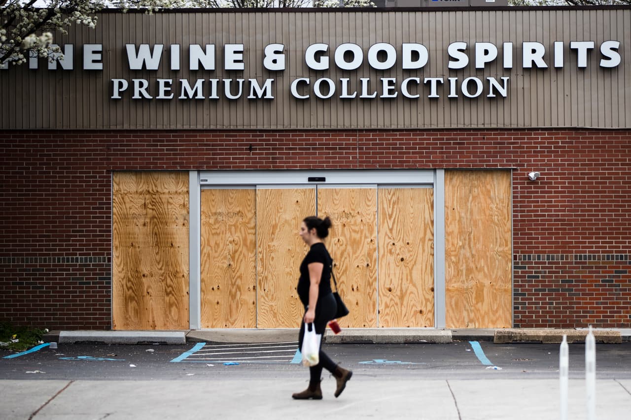 Una mujer pasa junto a una licorería cerrada en Filadelfia el 20 de marzo del 2020. El brote de coronavirus está causando estragos en la economía y forzando el cierre de negocios y el despido de gente. (AP Photo/Matt Rourke)