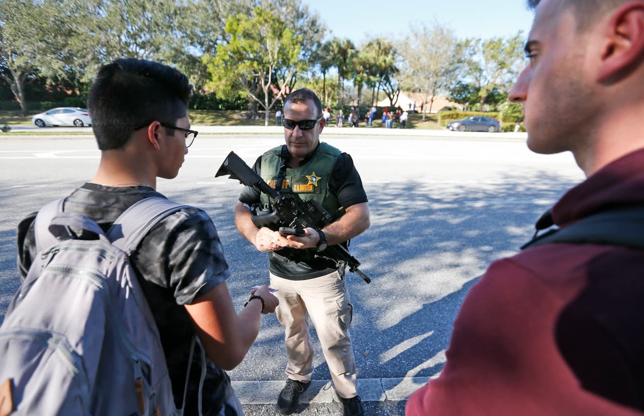 Un agente de la policía de Broward junto a los alumnos evacuados de la escuela.