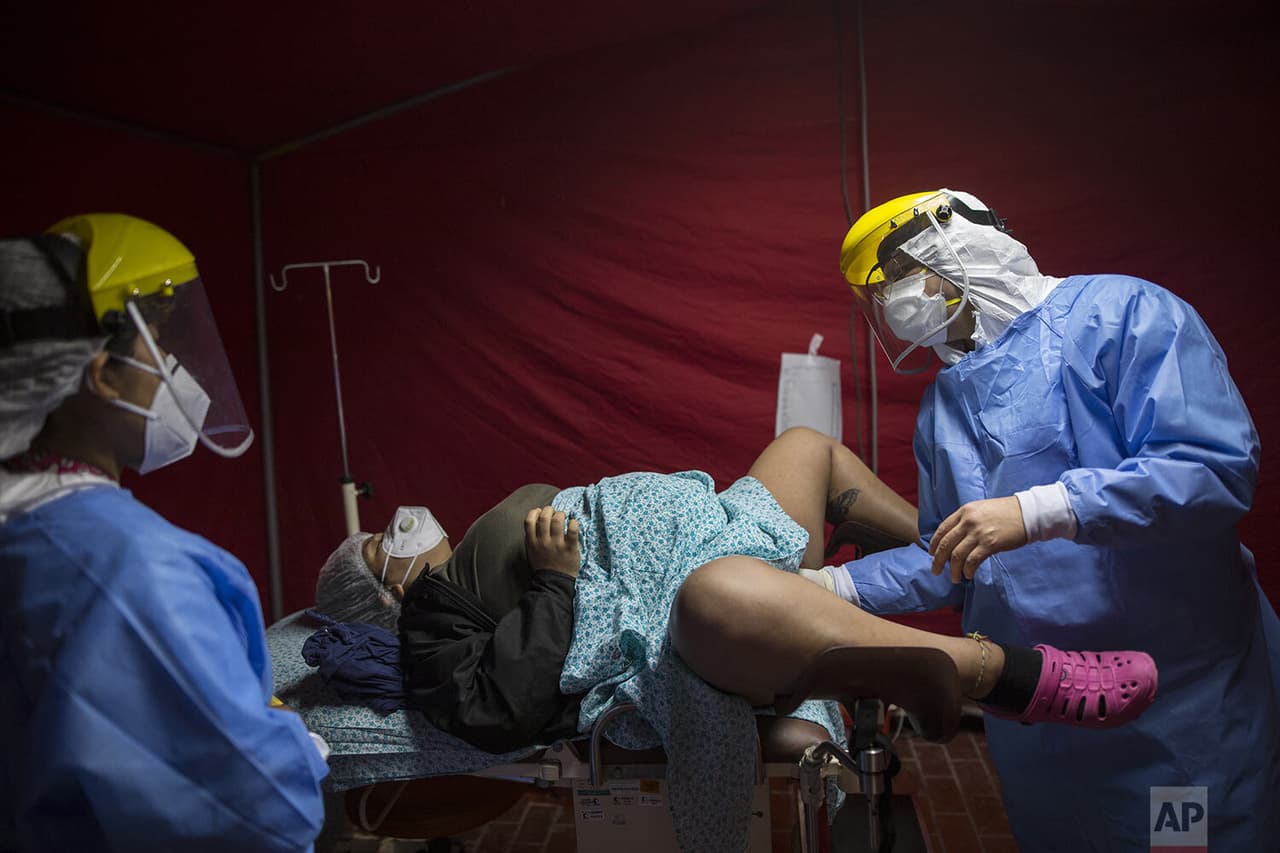 El Dr. Osvaldo Sierra mide la dilatación cervical de María Novella
<b> </b>dentro de una carpa roja habilitada para recibir a las mujeres embarazadas
<b> </b>con coronavirus.