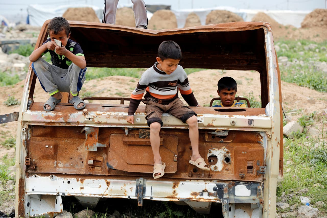 Tres niños juegan sobre un vehículo calcinado al sur de Mosul.