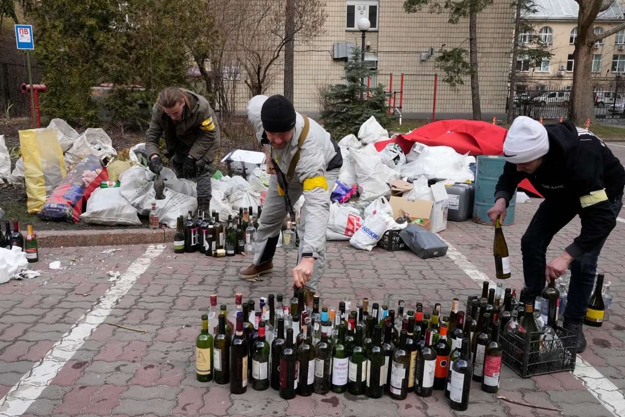 Miembros de las fuerzas civiles preparan cócteles Molotov en una plaza de Kiev, este domingo 27 de febrero de 2022.