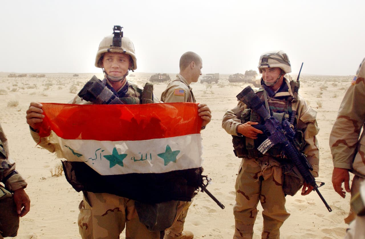 Un estadounidense muestra una bandera de Irak capturada en la frontera con Kuwait. A 21 dias de la invasión el presidente George W. Bush anunció que la misión se había completado, aunque el líder iraquí había escapado. La salida del gobernante devino en un complejo conflicto bélico interno que aún no ha finalizado.