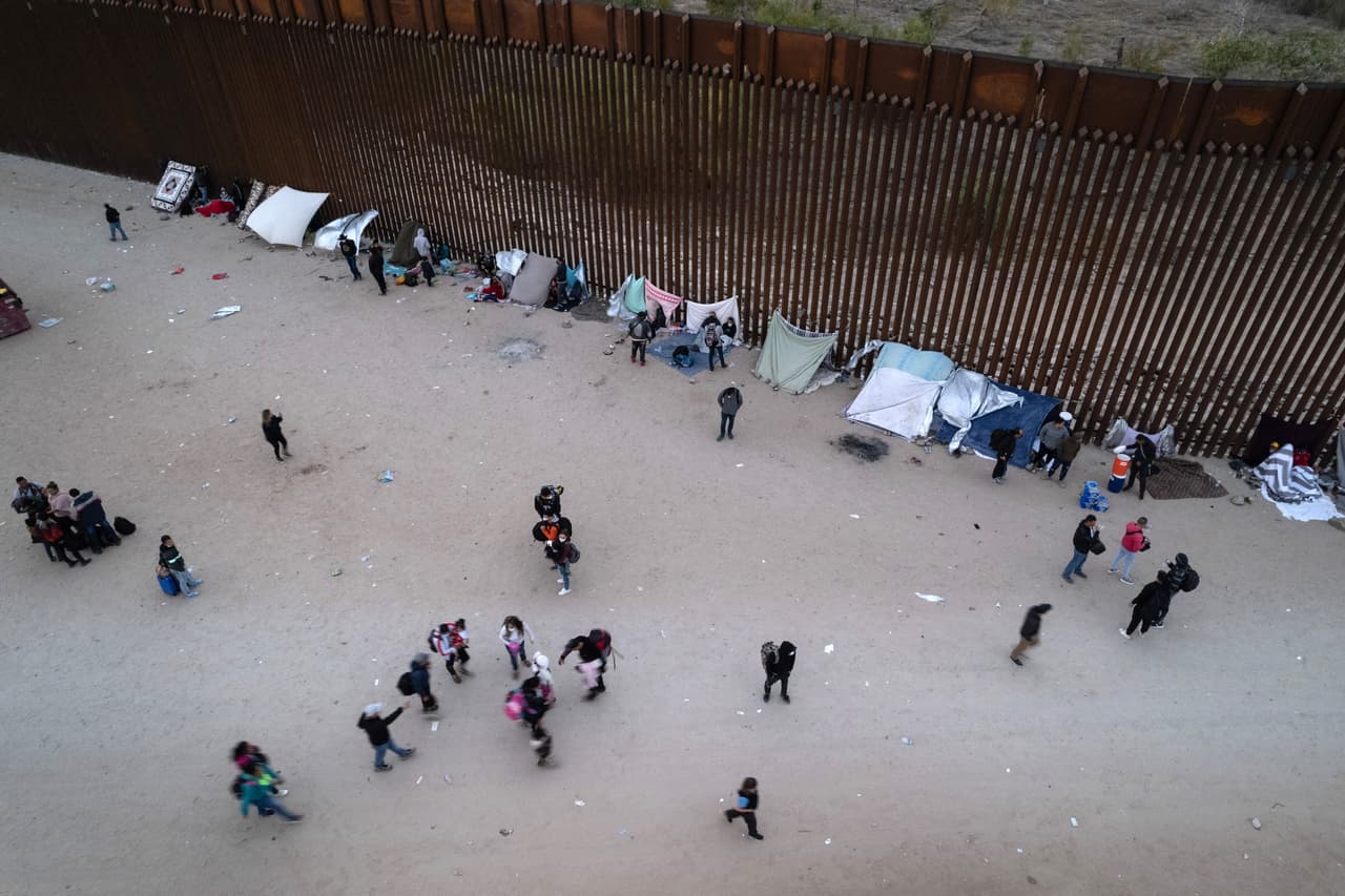Cientos de personas cruzan a territorio estadounidense caminando por la frontera de Yuma, algunos incluso con maletas, mientras esperan que llegue la Patrulla Fronteriza arman campamentos justo al lado del muro fronterizo.