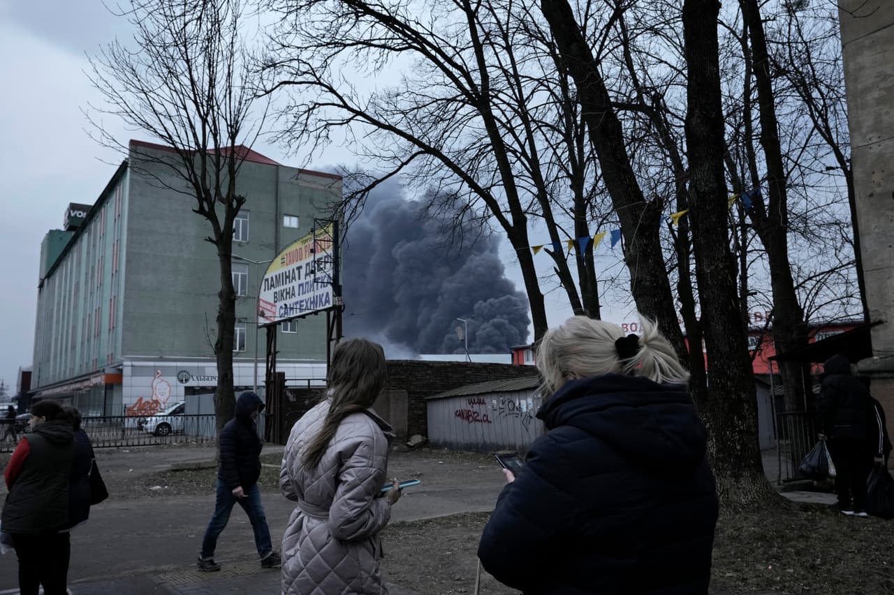 Al menos cinco personas resultaron heridas en ataques contra una instalación de almacenamiento de combustible cerca de la ciudad de Leópolis (Lviv), en el oeste de Ucrania, este sábado 26 de marzo de 2022. Las explosiones se producen 
<b>un día después de que el Ejército de Rusia dijera que el <a href="https://www.univision.com/temas/vladimir-putin">Kremlin</a> planeó concentrar su fuerza restante en arrebatar la totalidad de la <a href="https://www.univision.com/noticias/politica/ucrania-donbas-invasion-rusa-pretexto">región oriental de Ucrania, Donbas,</a></b> del control ucraniano. 
<br>
<br>En la foto, la gente mira la columna de humo que se eleva detrás de los edificios luego de que sonaran explosiones en las inmediaciones de Leópolis. 
<br>
