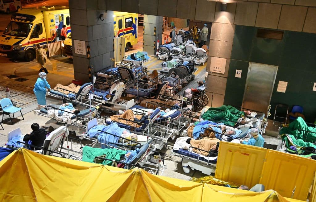 El colapso de los hospitales ha sido tal que muchos centros 
<b>han debido acomodar a los pacientes en camillas fuera de los edificios</b> en días cuando las temperaturas han bajado. En la imagen, el hospital Caritas. El colapso ha puesto a Hong Kong en una crisis tan descontrolada, que ha aumentado su dependencia de las autoridades de la Península: en las últimas semanas han enviado miles de doctores, enfermeras y constructores para dar respuesta a este brote.